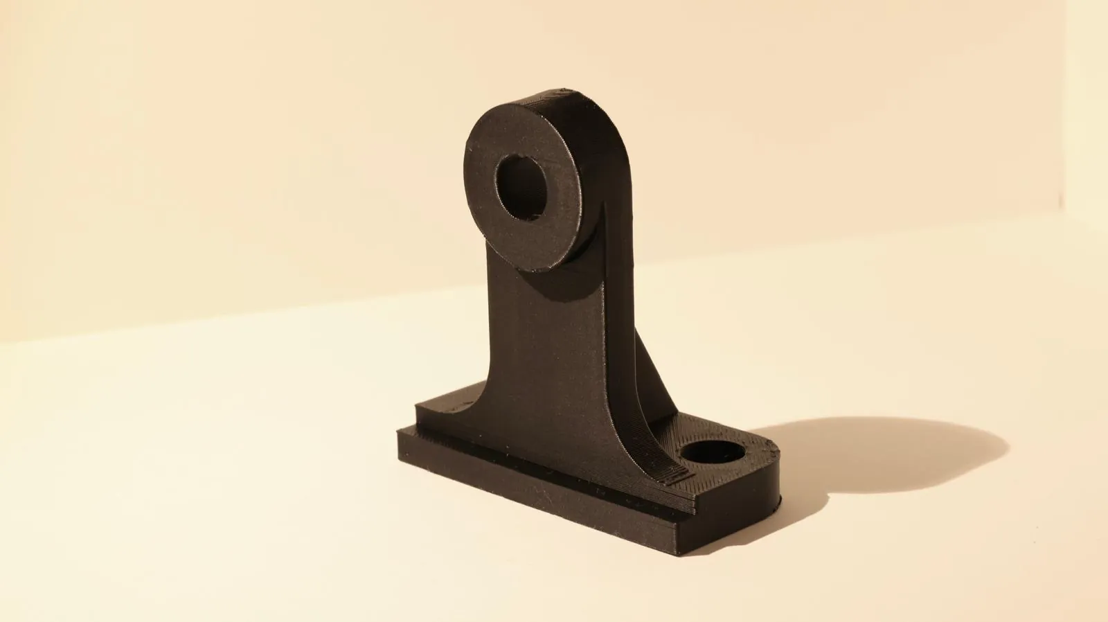 La staffa finita, in PETG nero, fotografata sul banco.