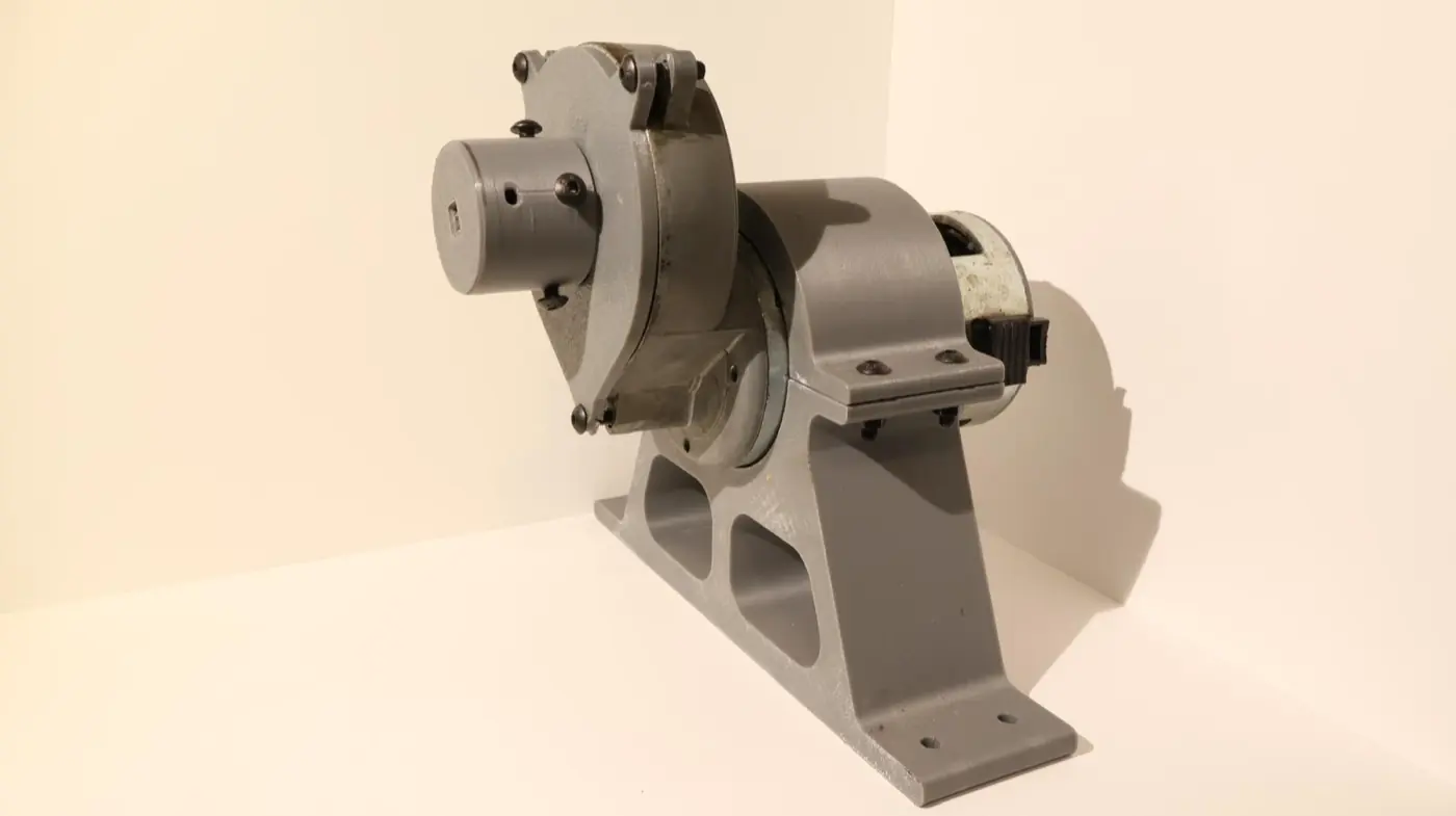 Supporto stampato in grigio che regge un motoriduttore metallico, con le nervature di alleggerimento alla base.