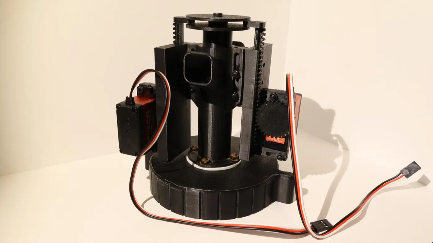Torretta orientabile nera stampata in 3D, con cremagliera, due servocomandi montati con bulloni e il cablaggio che esce dalla base.