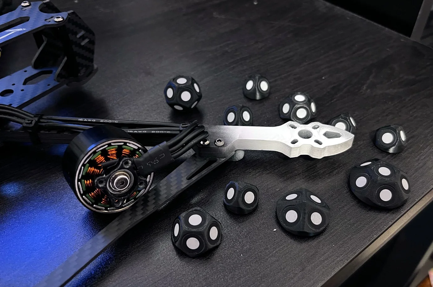 Il braccio di un drone sul tavolo, fra i marker a pallini bianchi.